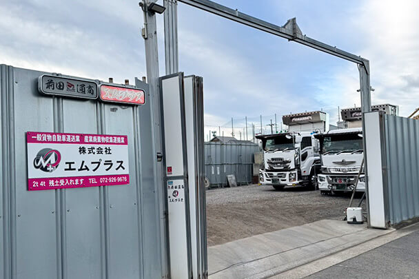 株式会社エムプラスの中継所入口と敷地内のダンプ車両