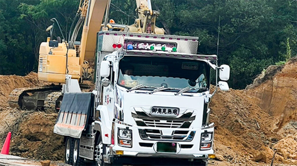 土砂を積載している10トンダンプ車と油圧ショベルが連携する現場風景