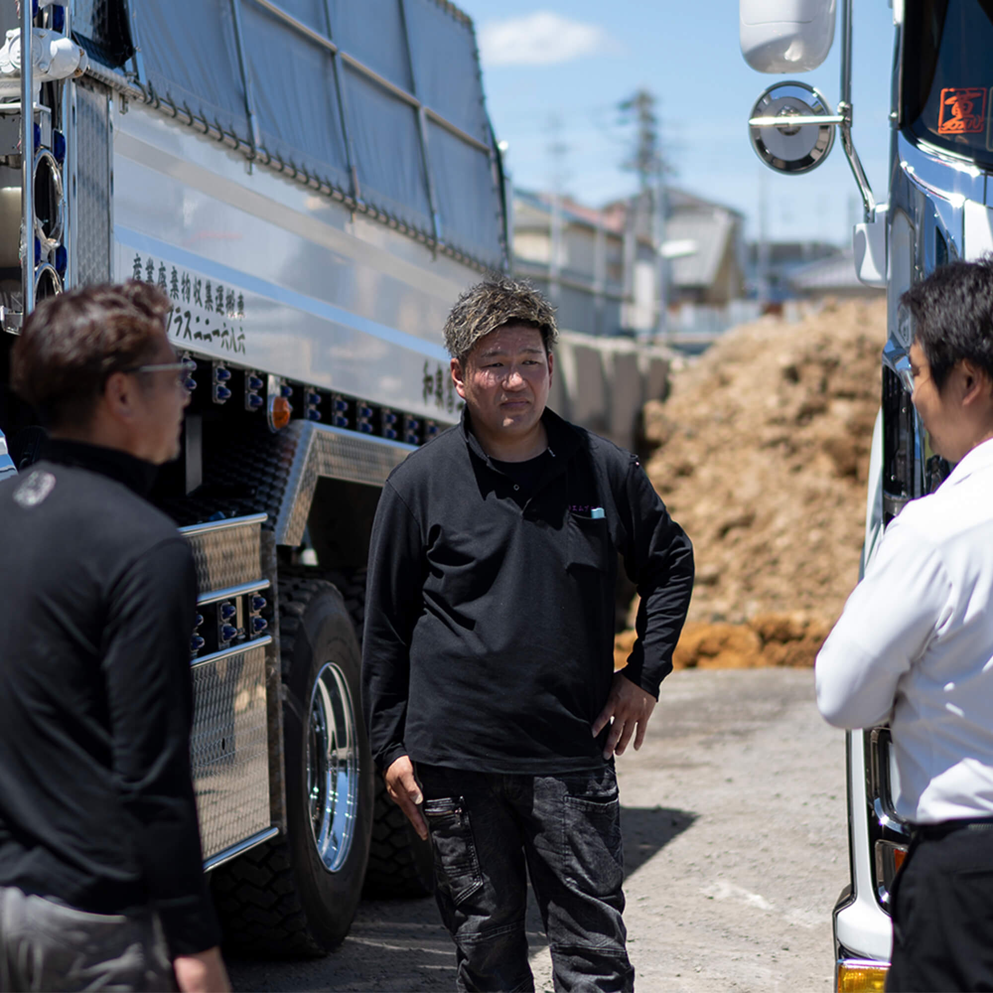 ダンプカーの横で会話する作業着姿の男性スタッフたち