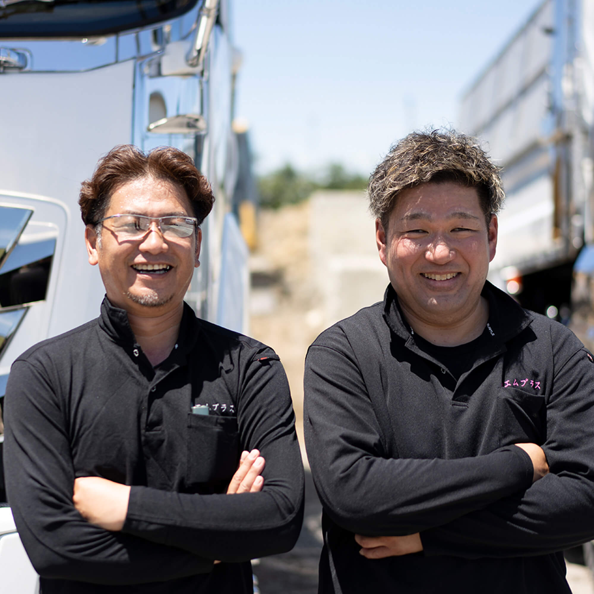 腕を組んで笑顔を見せる黒い制服の男性スタッフ2名