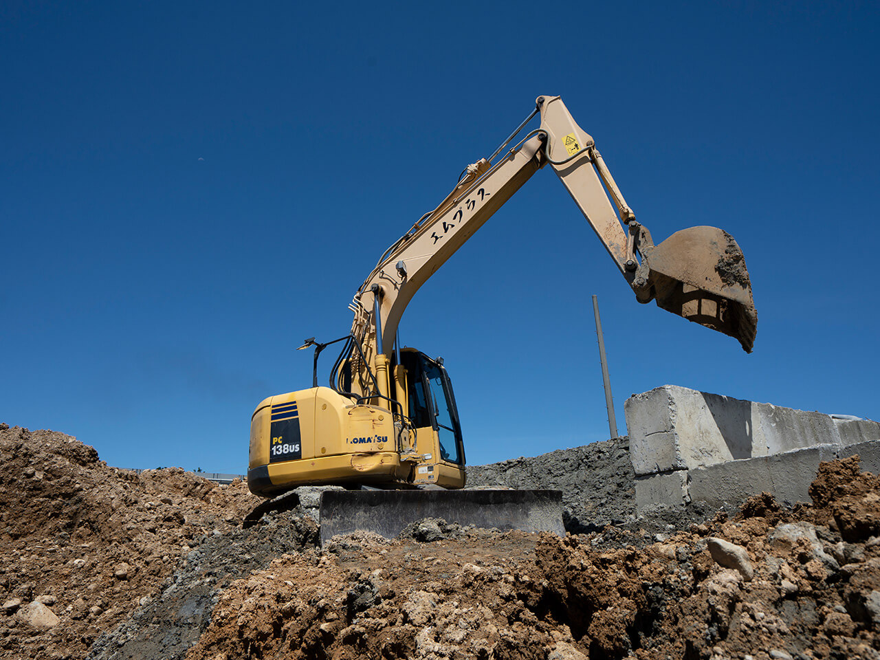 残土中継所で作業中のエムプラスの黄色いユンボ